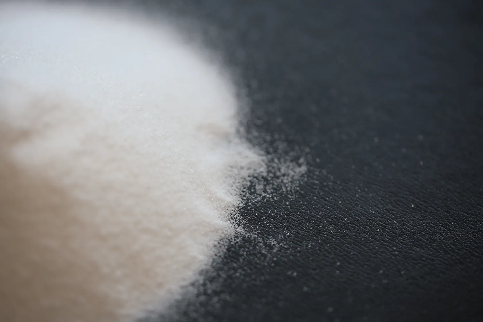 A close-up photograph of pale fine material on a dark surface