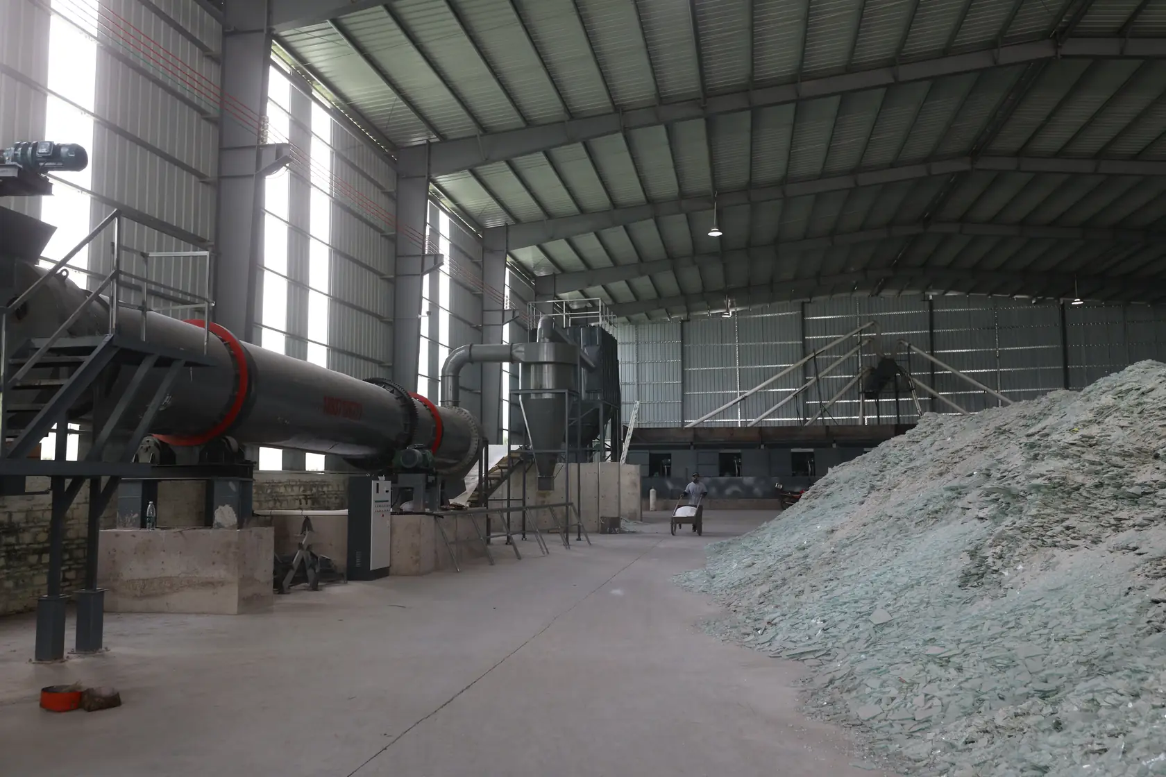 A view along the workshop with a rotary drum and glass fragments in the foreground